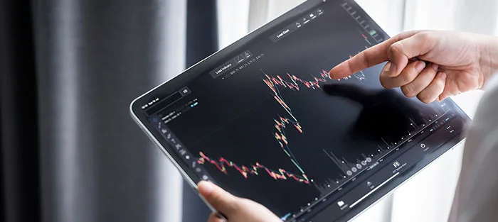 A hand pointing at a price chart on a tablet