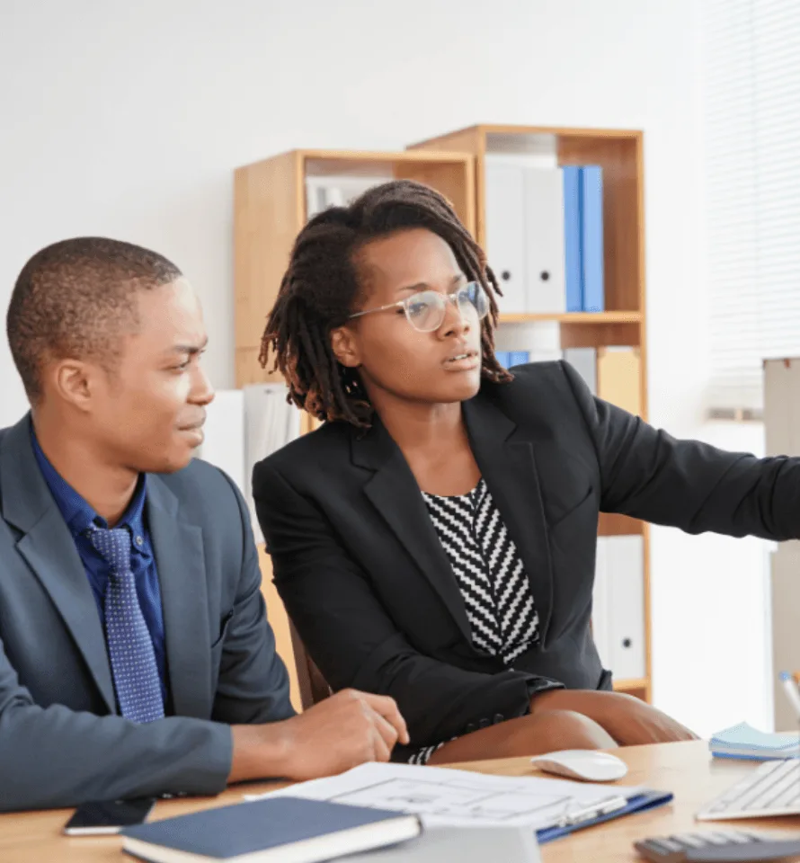 Two colleagues in suits reviewing work at a desk